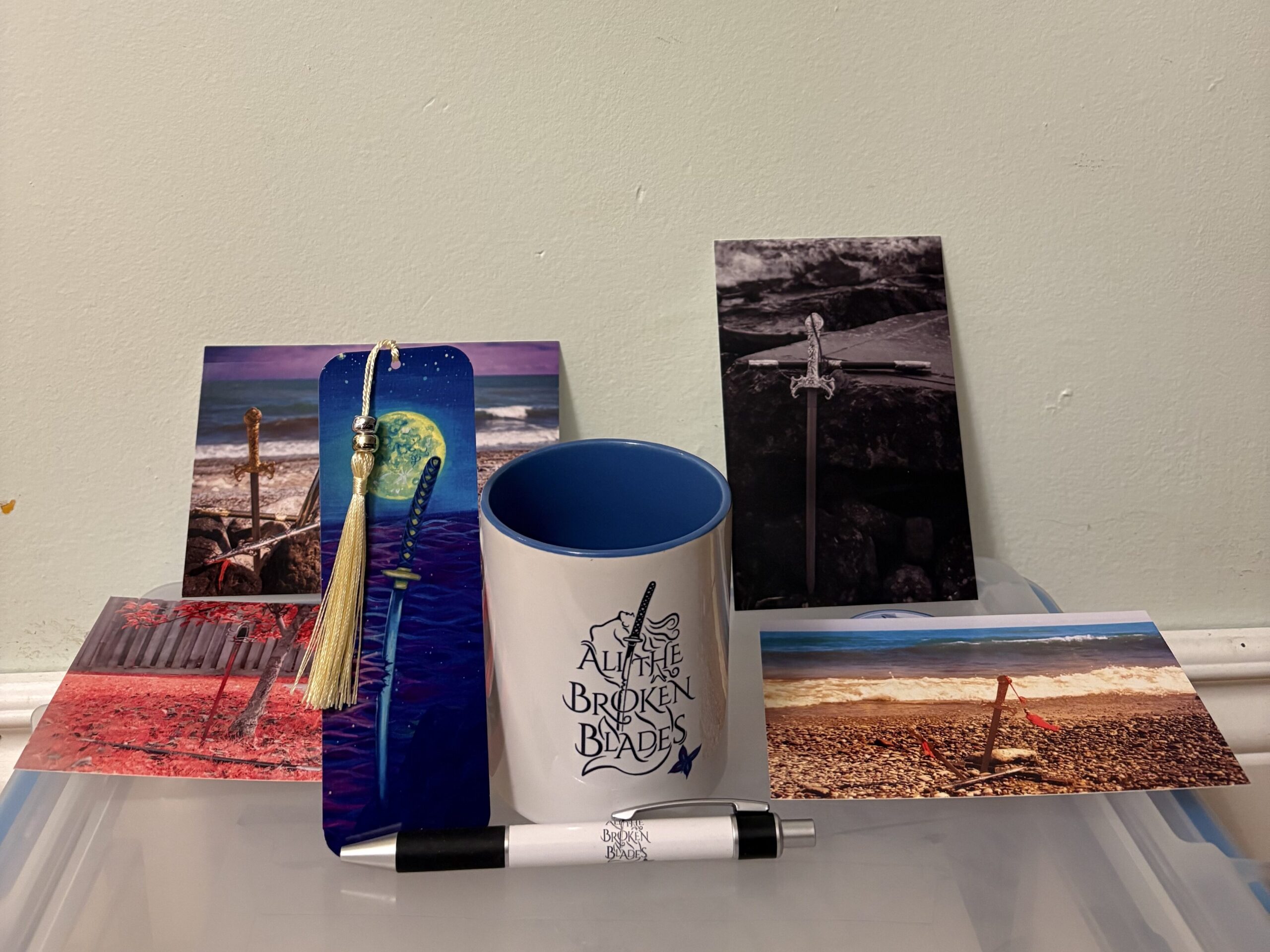 Picture of postcards, bookmark, pen, and mug - merchandise for ALL THE BROKEN BLADES by Y.M. Pang